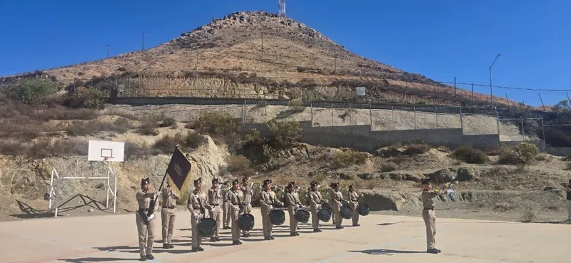 Banda de Guerra de uniforme caqui con su guion durante una presentación al aire libre