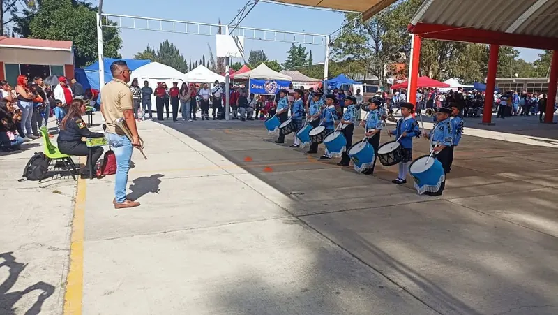 Banda de Guerra infantil de uniforme azul mientras una jueza califica su presentación